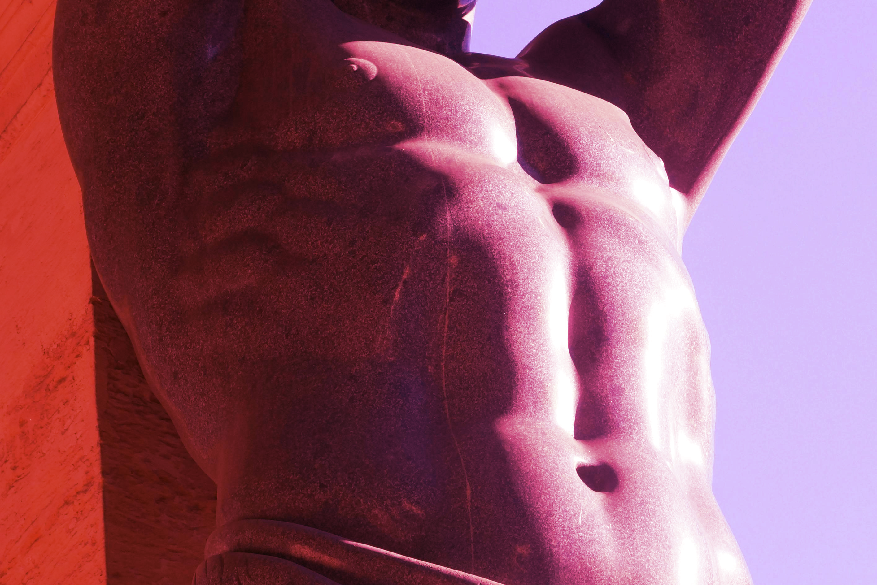 Pink tinted closeup of a marble statue's torso